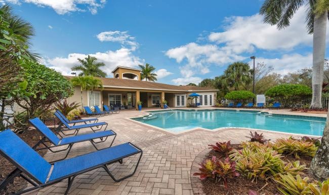 a pool with chairs and a building in the background